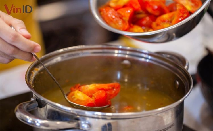 Nồi nước dùng bánh đa cua rau muống được nêm nếm gia vị và cà chua thơm ngon