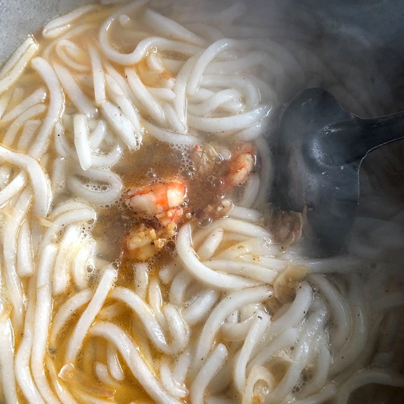 Cho thịt thăn heo đã xào vào nồi bánh canh bột lọc đang sôi lăn tăn