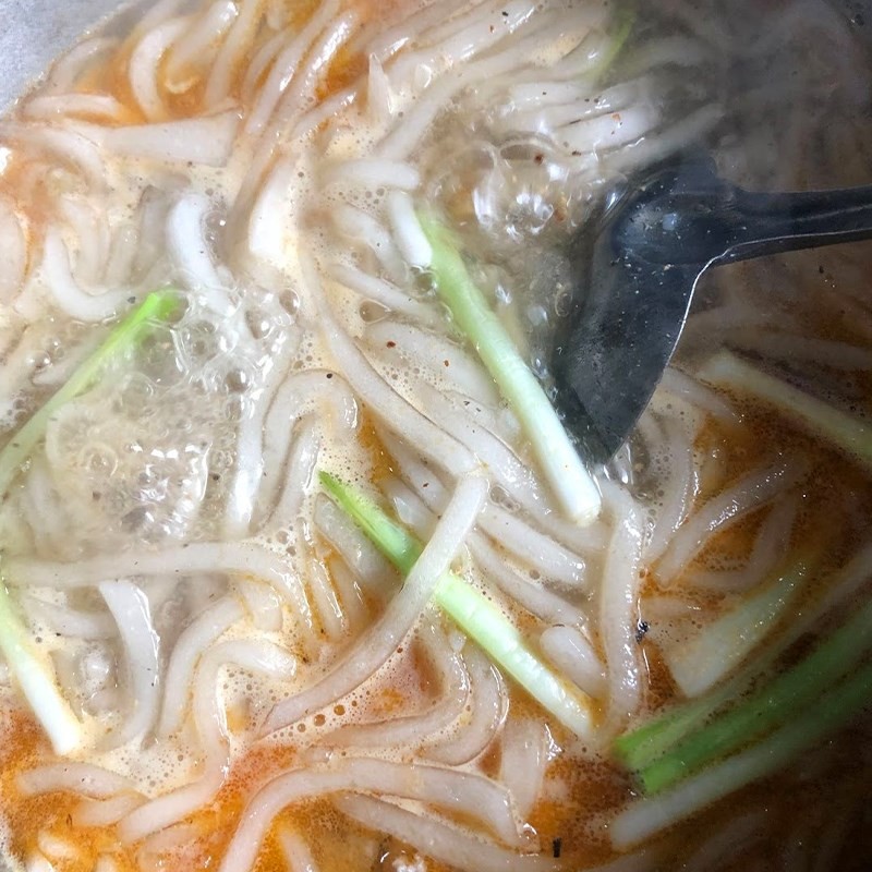Thêm tôm đã xào vào nồi bánh canh bột lọc, khuấy đều để hương vị hòa quyện