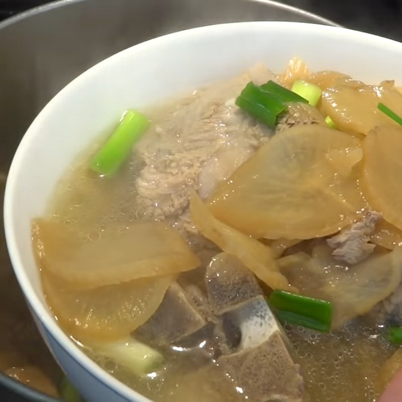 Múc canh củ cải muối nóng hổi ra tô, sẵn sàng để thưởng thức cùng gia đình, thể hiện thành quả cách nấu canh củ cải muối