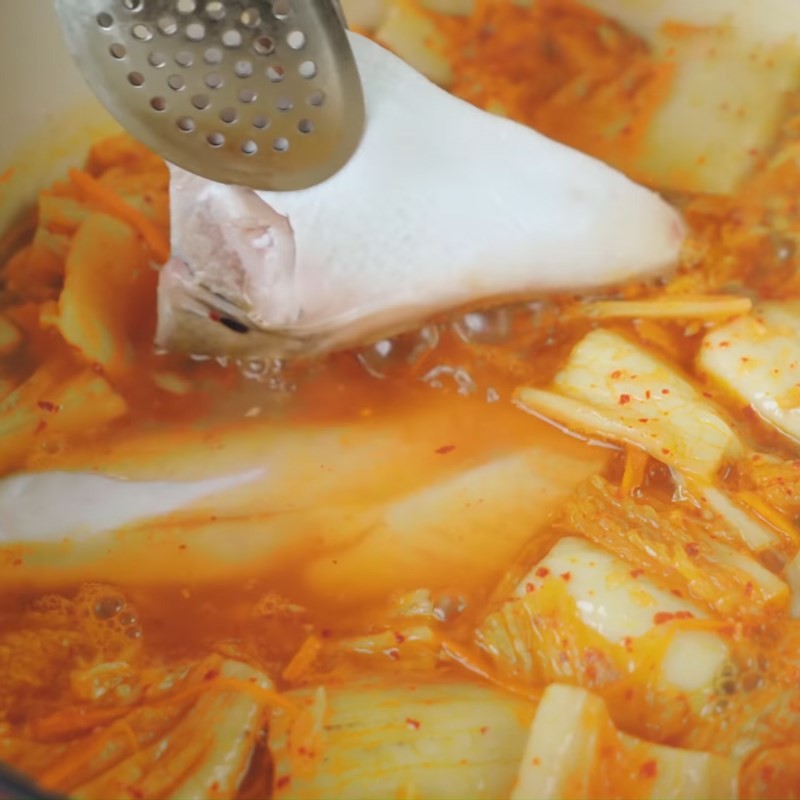 Cho cá hồi vào nồi canh kim chi đang sôi để hoàn thành món ăn