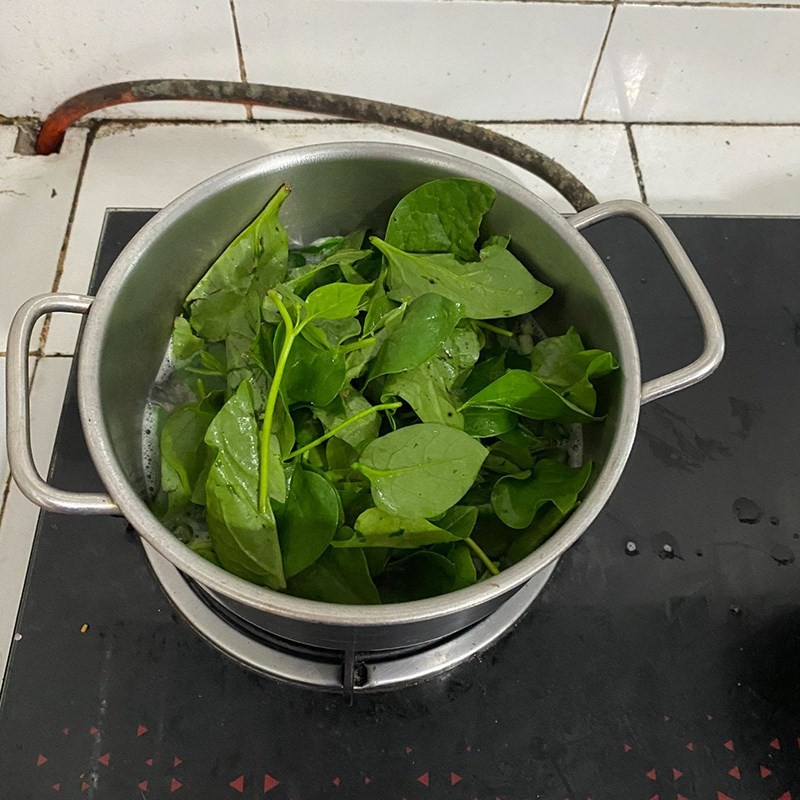 Thêm rau mồng tơi vào nồi canh hến đang sôi
