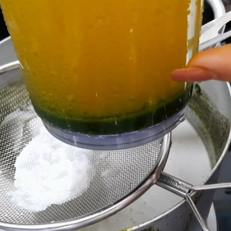 Hỗn hợp nước cốt dừa và nước cốt lá dứa đang được nấu trên bếp với lửa nhỏ, tạo độ sánh và hương thơm cho xôi mặn lá dứa