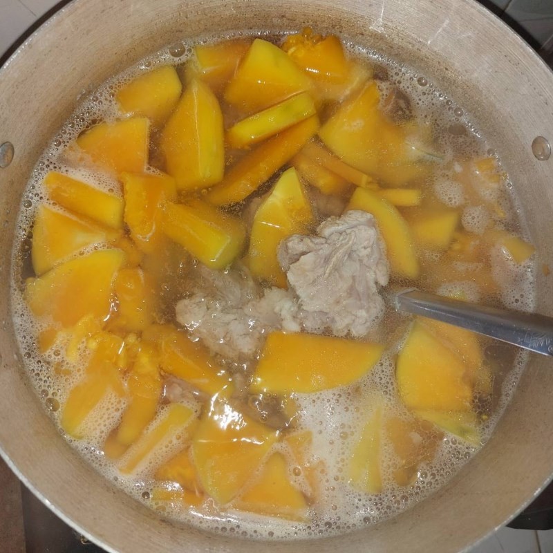 Cho đu đủ vào nồi xương hầm đang sôi để nấu canh thịt hầm