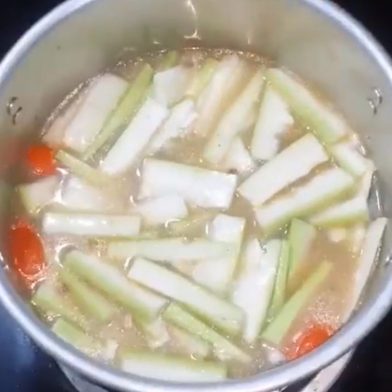 Cho bầu vào nồi nước luộc trai, nấu canh trai bầu mồng tơi đang sôi