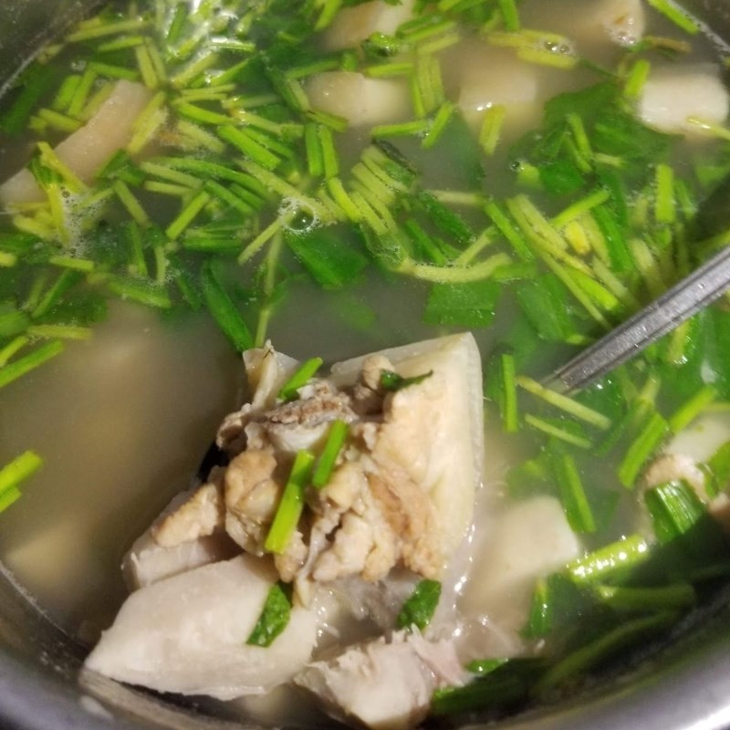 Thêm rau thơm vào nồi canh đuôi heo hầm khoai môn trước khi tắt bếp