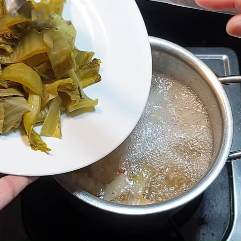 Cho cải chua và các loại gia vị vào nồi canh