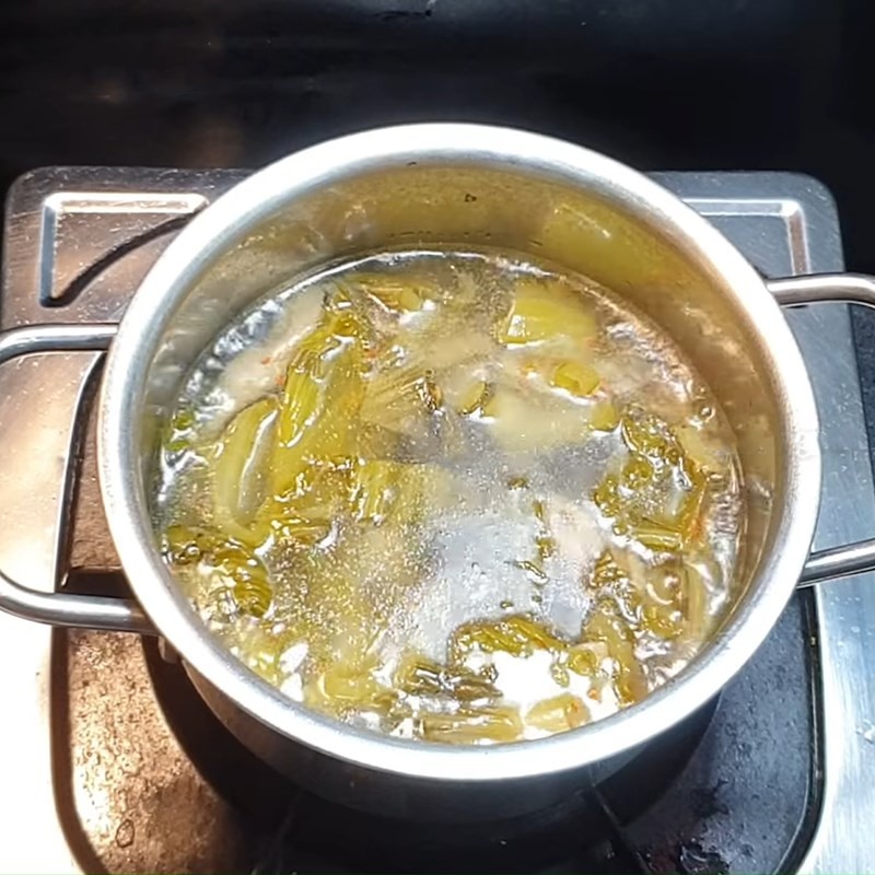 Rắc hành lá băm nhỏ vào canh cải chua chay mì căn trước khi tắt bếp