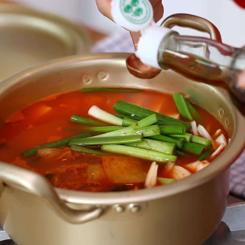 Thêm cá ngừ vào nồi canh kim chi đang sôi để hoàn thành