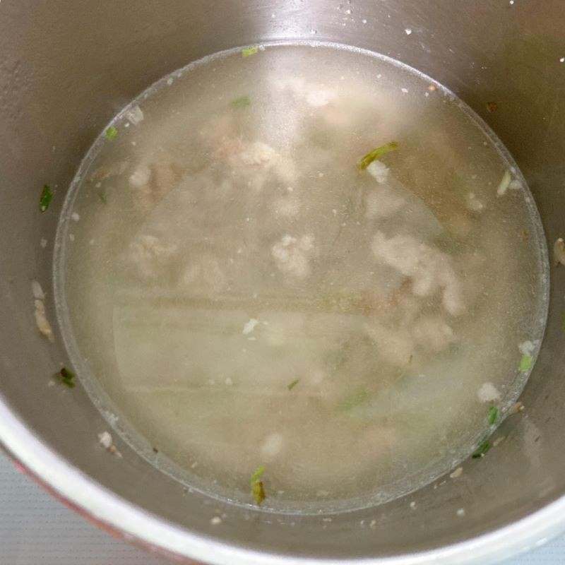 Hình ảnh cà chua đang được thêm vào nồi canh thịt băm đang sôi