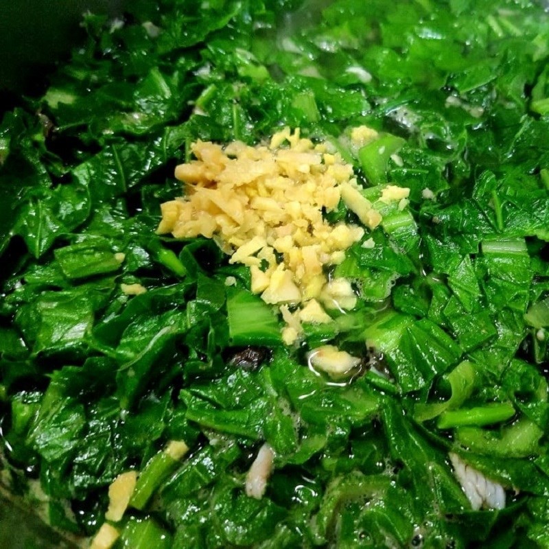 Cho rau cải vào nồi canh cá rô đang sôi