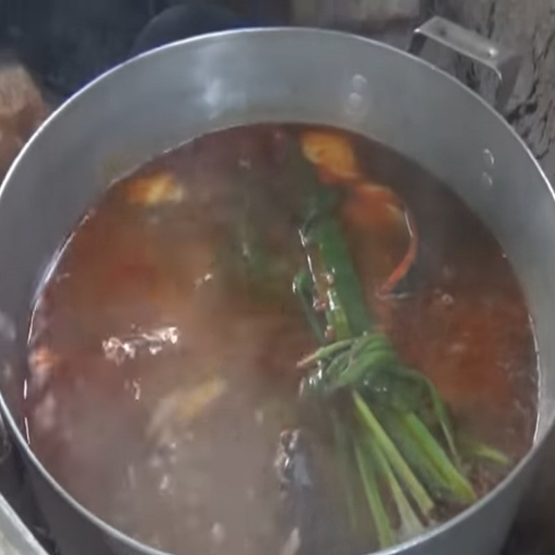 Cho thơm và cá chạch đã chiên vào nồi nước lẩu đang sôi