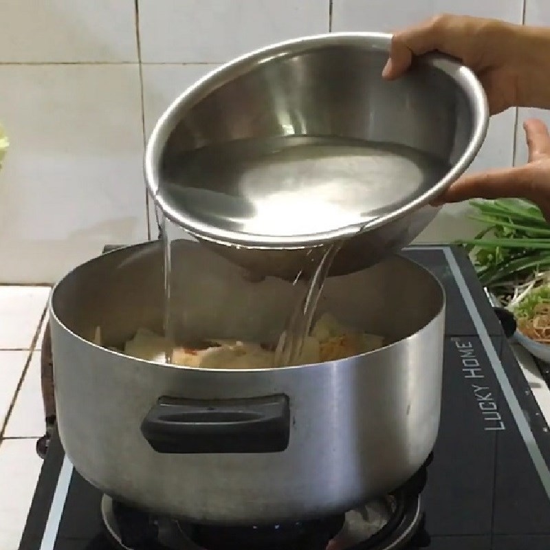 Đổ nước dừa tươi vào nồi và đun sôi để nấu lẩu cá lóc măng chua