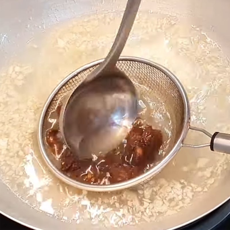 Thêm me vắt vào rây, nhúng vào nước sôi để lấy cốt chua cho nước lẩu