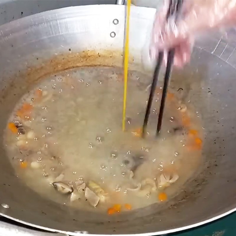 Nồi súp gà hạt sen đang được khuấy đều với trứng và bột năng