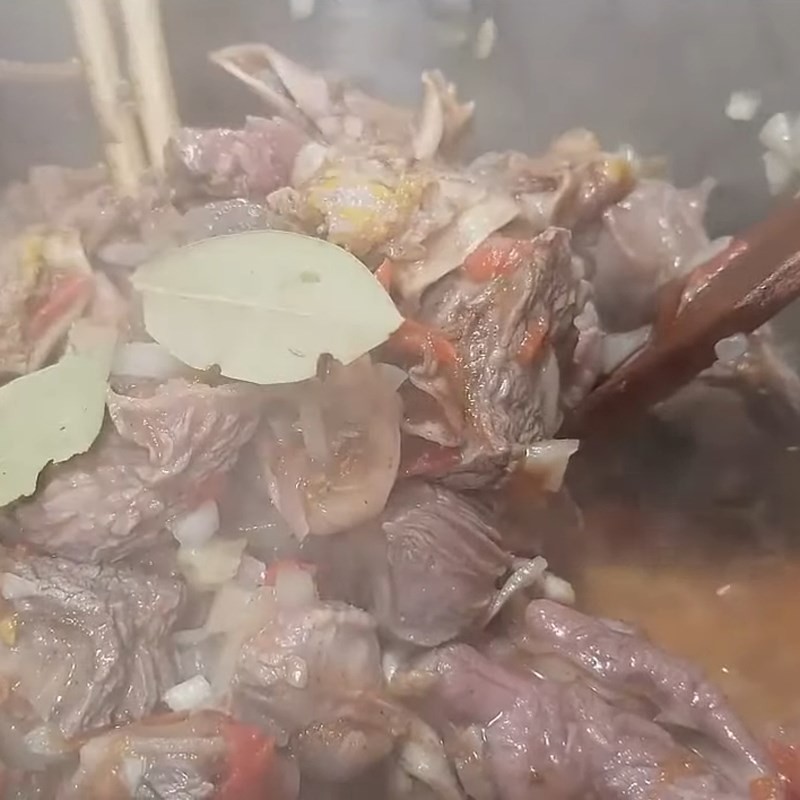 Nồi thịt bò sau khi đã xào, giờ được thêm sốt cà chua và lá nguyệt quế để hầm