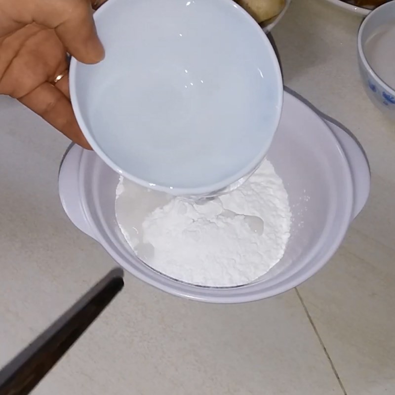 Thao tác pha bột năng với nước ấm trong bát nhỏ