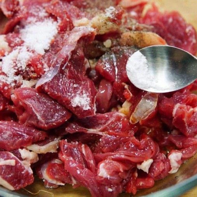Ướp thịt bò với các loại gia vị để chuẩn bị nấu mướp xào thịt bò