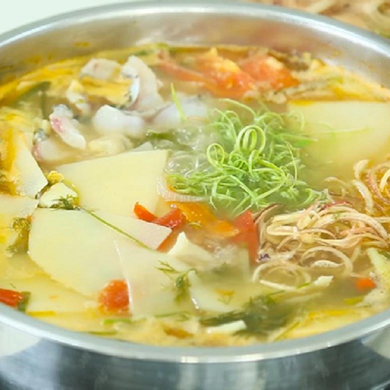 Gắp miếng cá lóc trong nồi lẩu cá lóc măng chua để thưởng thức