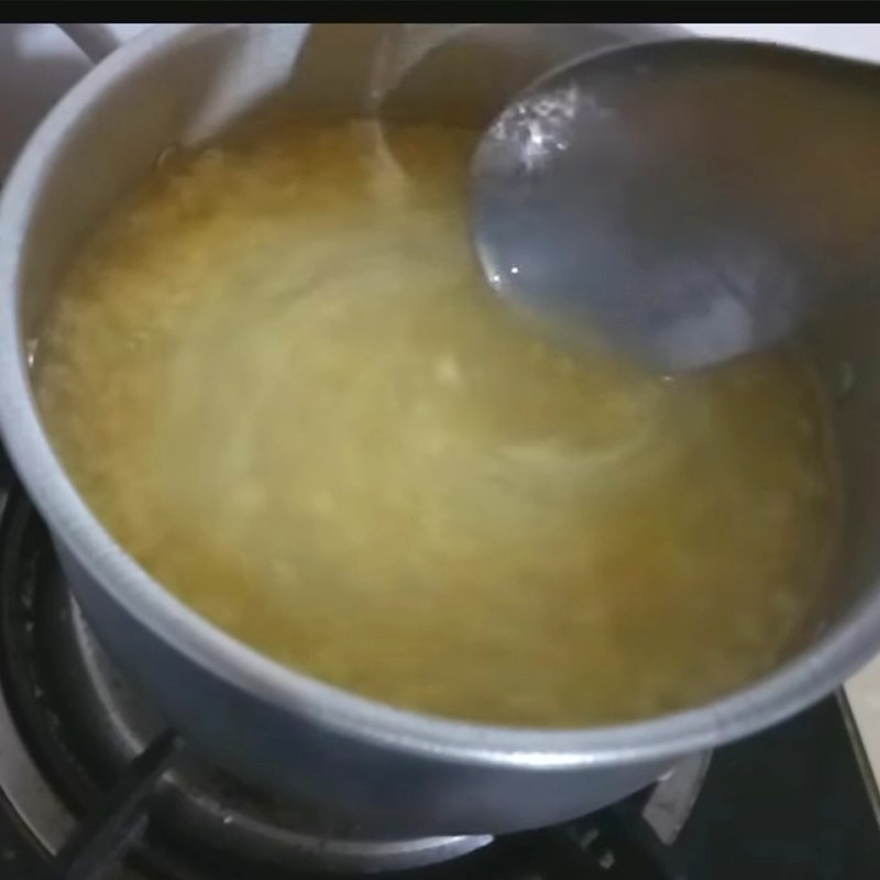 Đang khuấy đều hỗn hợp nước dừa, đậu xanh và đường để tạo phần nước chè sánh mịn