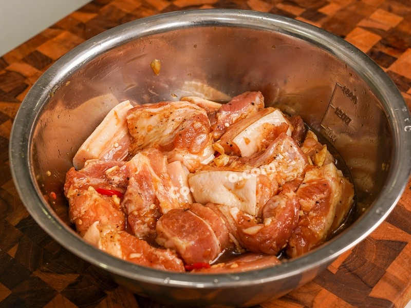 Thịt ba chỉ đang được ướp với gia vị đậm đà trong tô, bước quan trọng trước khi kho thịt bằng nồi nấu chậm