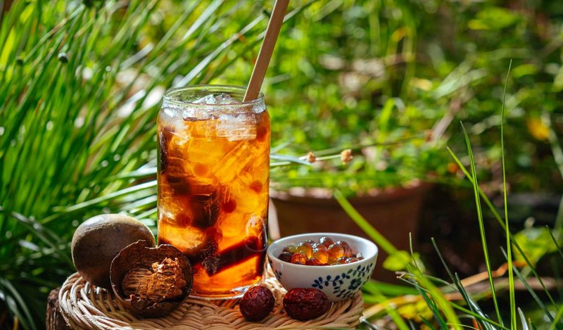 Một ly nước La Hán quả đặt trên bàn gỗ, gợi ý về việc sử dụng nước La Hán như một phần của chế độ ăn uống hỗ trợ giảm cân nhưng cần có sự kiểm soát.