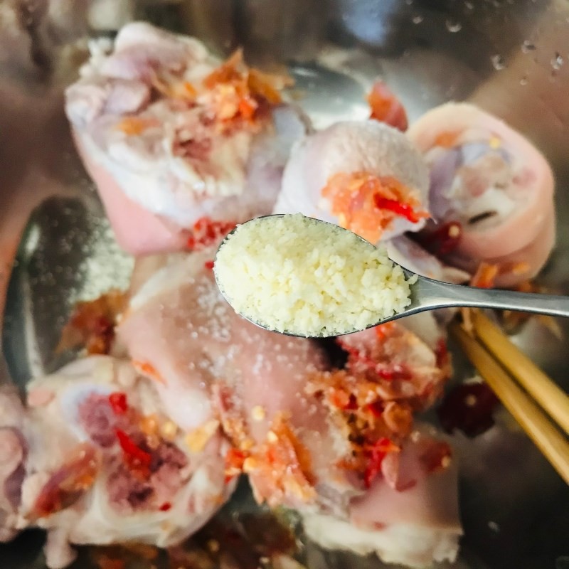 Ớt và hành khô đang được giã nhuyễn để tạo hỗn hợp gia vị ướp giò heo, tăng cường hương vị đặc trưng của món lagu