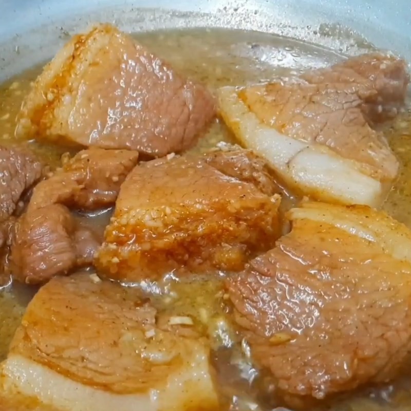 Thịt lợn đang được khìa liu riu trong nước sốt đậm đà, đảm bảo miếng thịt mềm, thấm vị cho món xôi mặn lá dứa