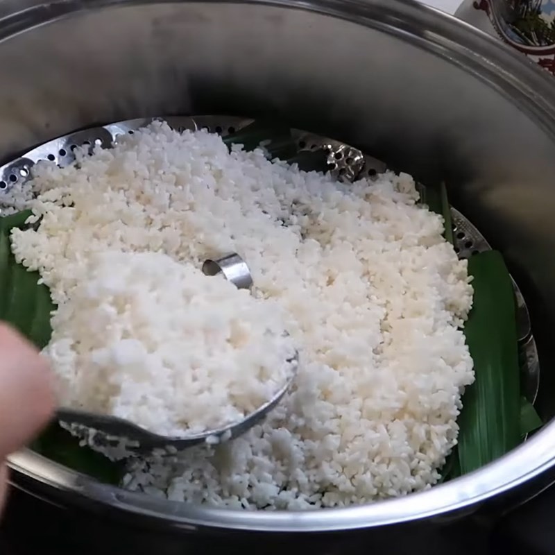 Cho gạo đã ngâm vào xửng hấp có lót lá dứa, chuẩn bị cho quá trình nấu cơm bằng cách hấp