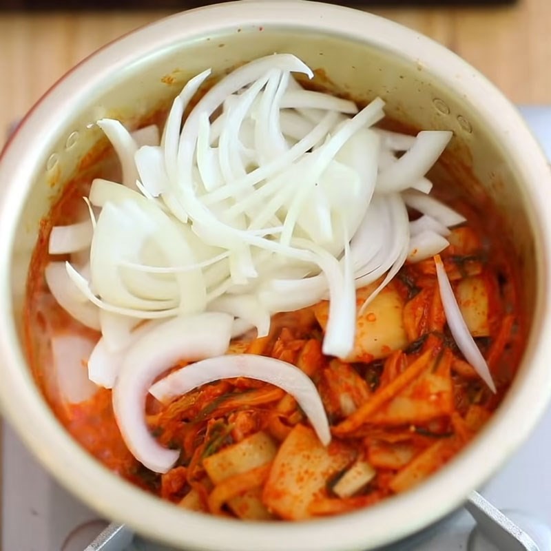 Xếp đậu hũ và hành lá vào nồi canh kim chi cá ngừ ngâm dầu