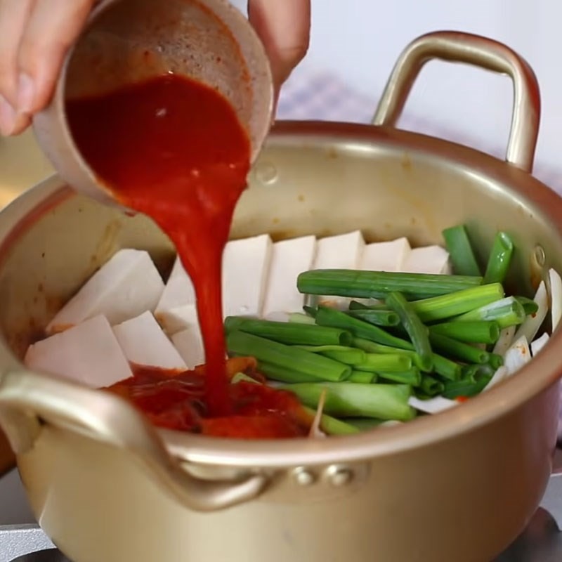 Đổ nước sốt kim chi vào nồi canh để tạo hương vị đậm đà