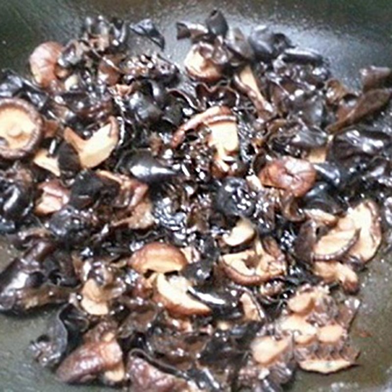 Nấm hương và mộc nhĩ đang được xào trên chảo với hành tím phi thơm, tạo hương vị đậm đà.