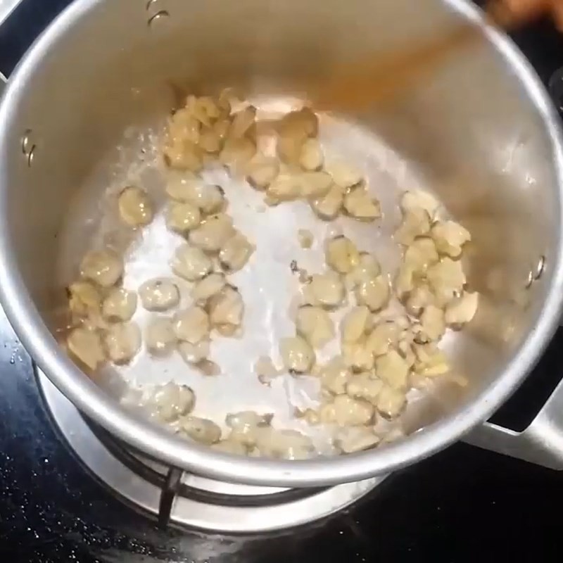 Thịt ngao đang được xào trên chảo, chuẩn bị hòa quyện với cà chua và gia vị