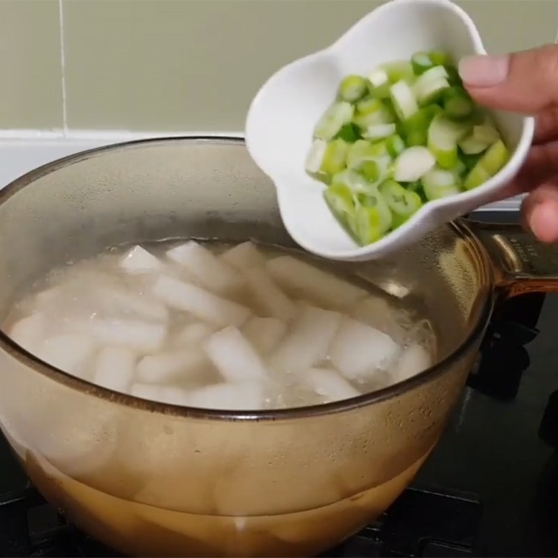 Rắc hành boa rô thái nhỏ lên tô canh thịt bò củ cải kiểu Hàn Quốc nóng hổi trước khi dùng