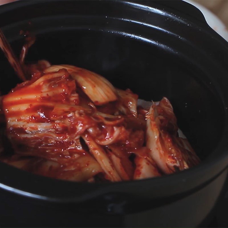 Đảo đều thịt ba chỉ và kim chi để thấm vị trước khi thêm nước