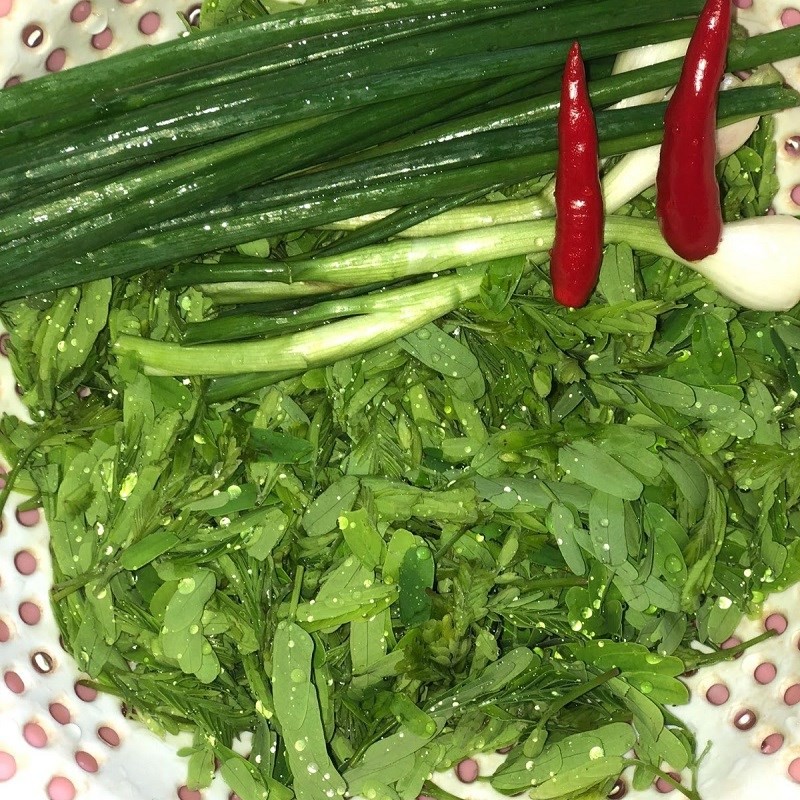 Rửa sạch lá me non chuẩn bị cho món canh cá me chua
