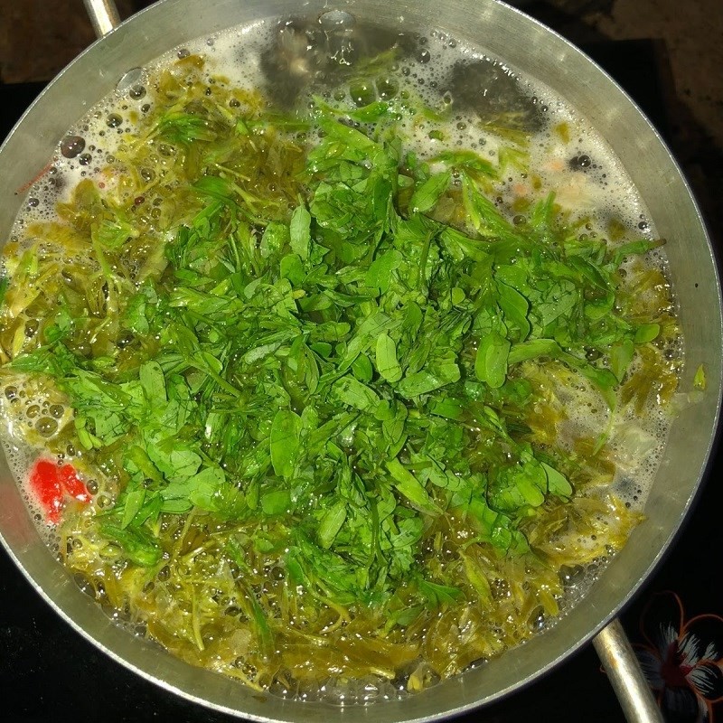 Thêm lá me non đã vò nhẹ vào nồi canh cá me chua đang sôi