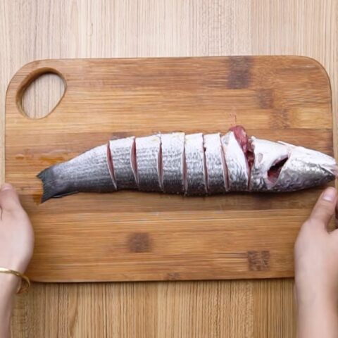 Ướp cá lóc với gia vị để chuẩn bị nấu canh chua