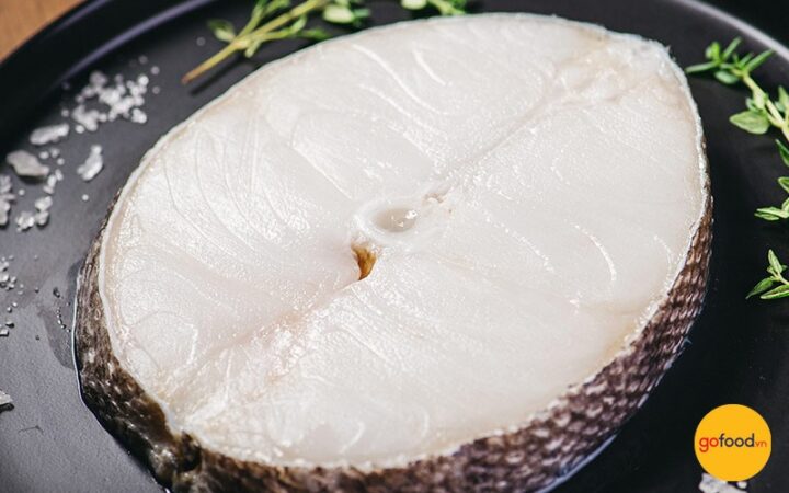 Mâm lẩu cá tuyết nóng hổi với nước dùng vàng óng và các loại rau ăn kèm