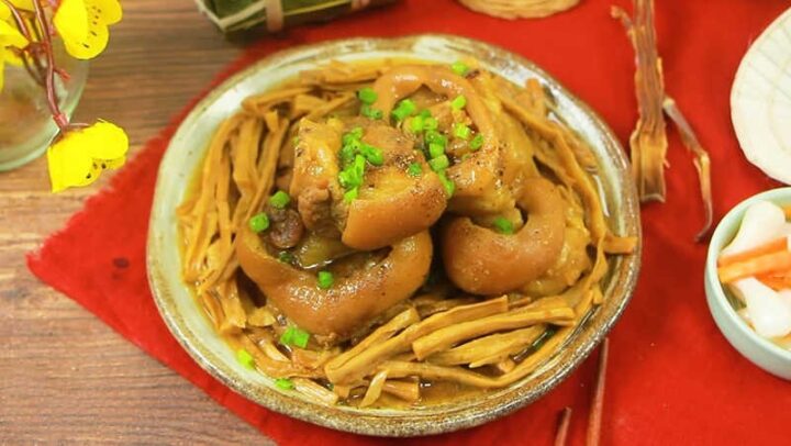 Hình ảnh món canh măng chân giò heo nóng hổi, màu vàng nâu hấp dẫn, trang trí hành lá