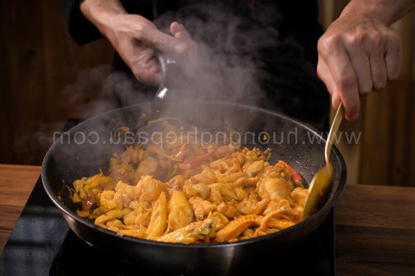 Chảo thịt gà và tôm đang được xào chín thơm cùng gia vị