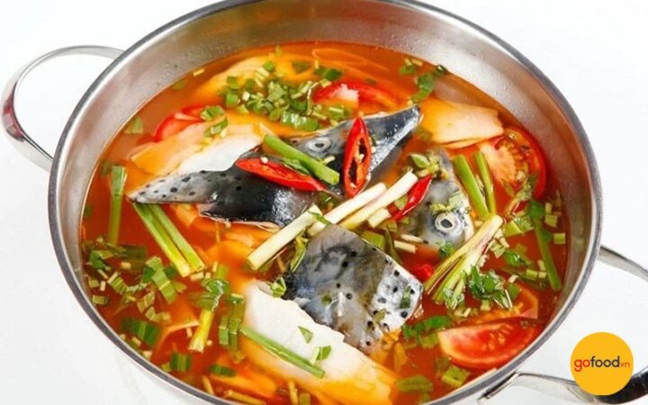 Nồi lẩu cá hồi măng chua nóng hổi, nghi ngút khói, ăn kèm rau sống