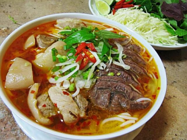 Tô bún bò Đà Lạt nóng hổi với thịt bò, giò heo, và rau sống đặc trưng, minh họa cách nấu bún bò Đà Lạt hấp dẫn.