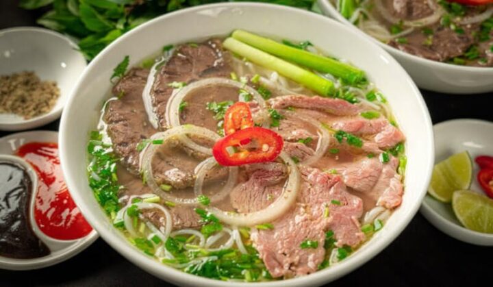 Tô phở bắp bò nóng hổi với thịt bắp bò thái lát, hành ngò, và nước dùng trong, thể hiện thành quả của cách nấu phở bắp bò thành công.