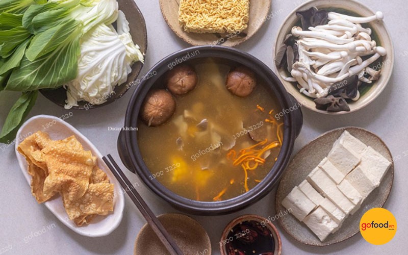 Nồi lẩu nấm chay thập cẩm đầy màu sắc với nhiều loại nấm, rau củ và tàu hũ ky, bốc khói nghi ngút hấp dẫn.